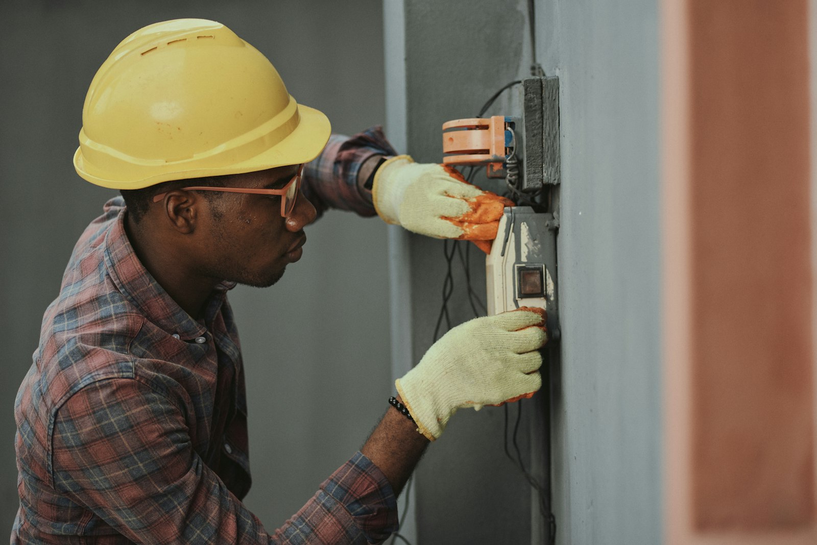 Elektrikář v helmě instaluje elektroinstalaci na hrubé stavbě